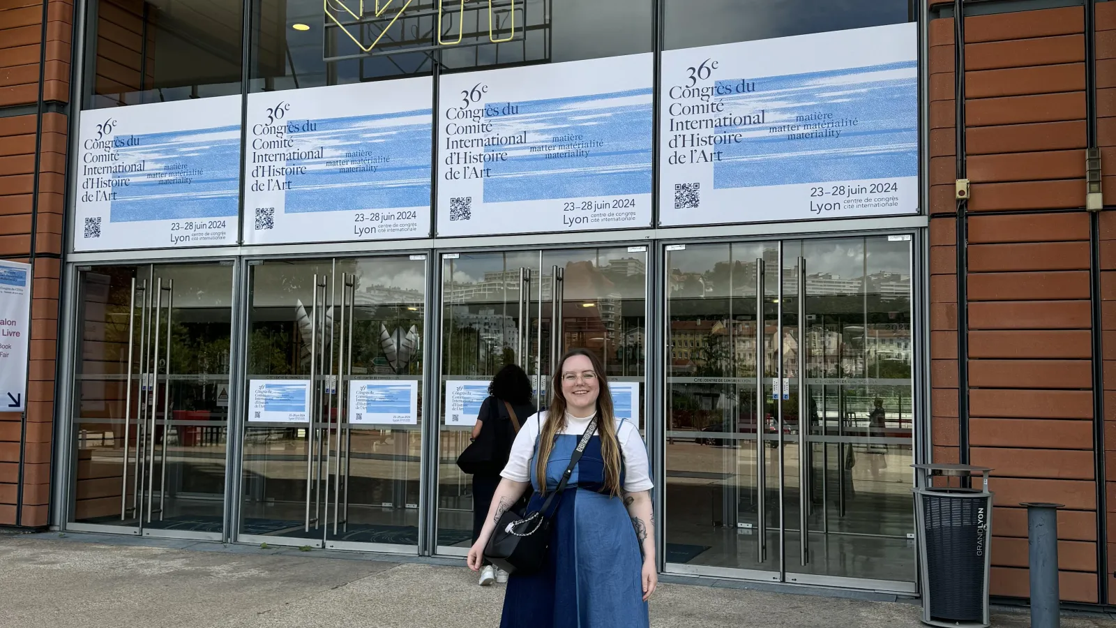 April Riddle standing outside the entrance to the 36th World Congress in Lyon, France