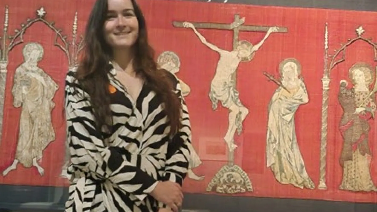 Emilela Thomas-Adams standing in front of a tapestry
