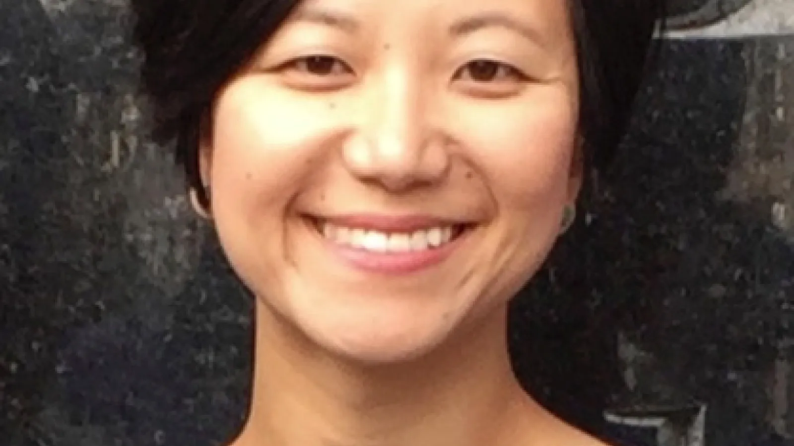 Yang Wang wearing a navy top in front of a marble wall