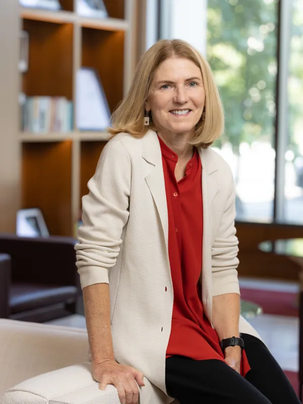 Professor Lisa Florman seated on the edge of a couch in the lobby of a building